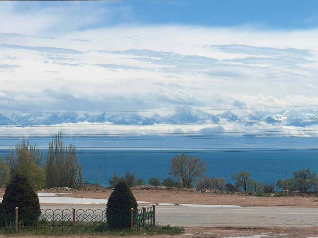 Large blue lake with a distant snow-covered mountain range under clouds.
