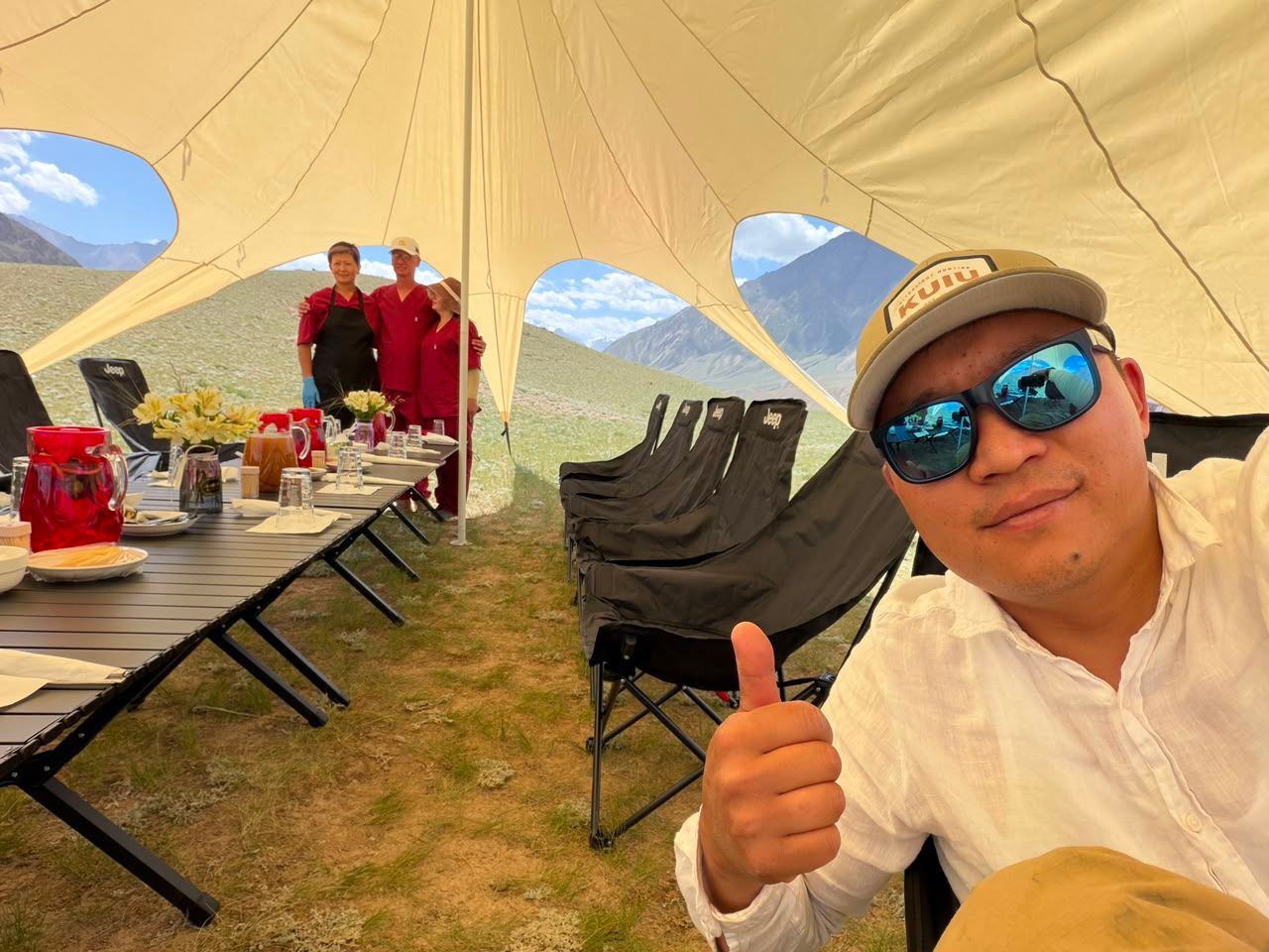 Kylych giving a thumbs-up inside the expedition camp dining canopy.