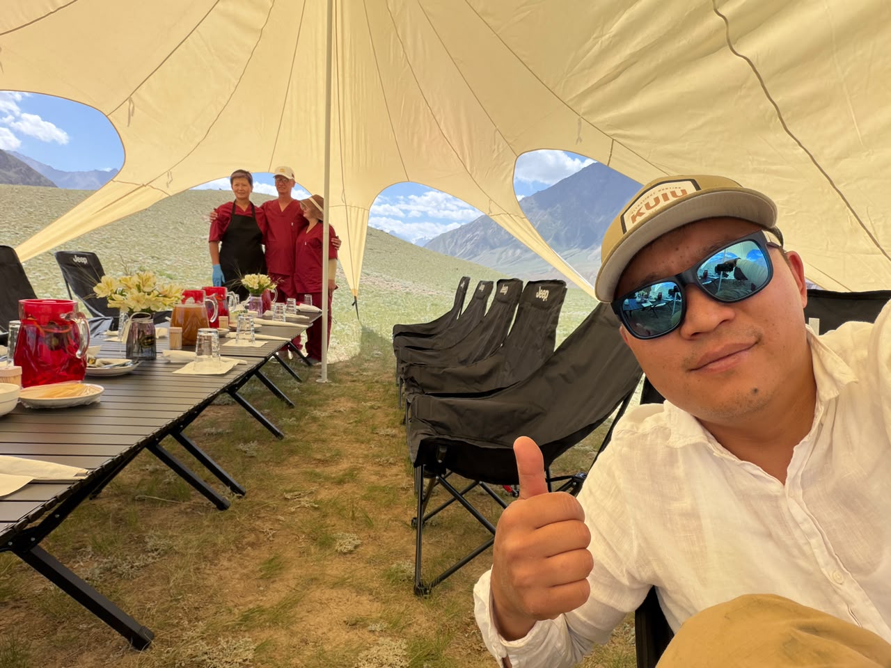 Kylych giving a thumbs-up inside the expedition camp dining canopy.